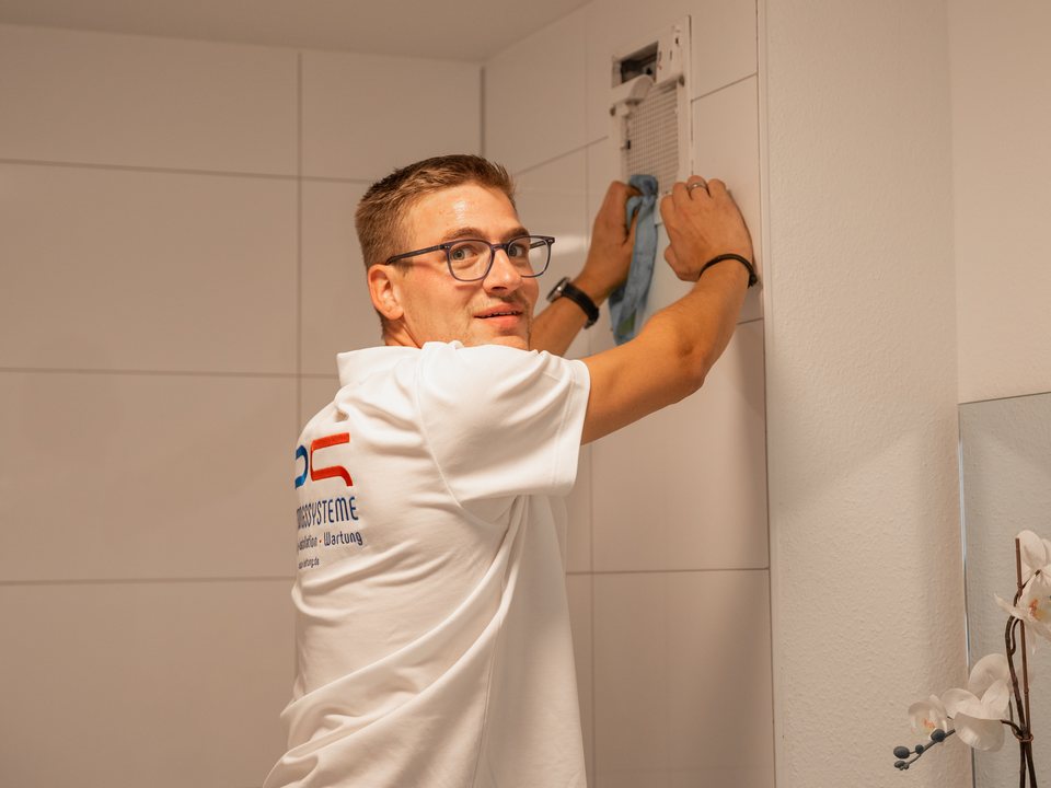 Techniker reinigt ein Lüftungsgerät im Bad
